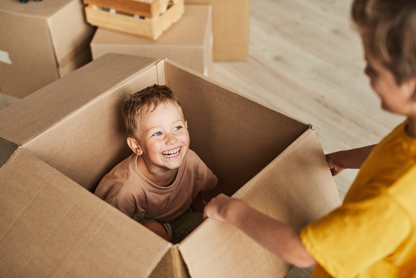 kid smiling in cardboard moving box