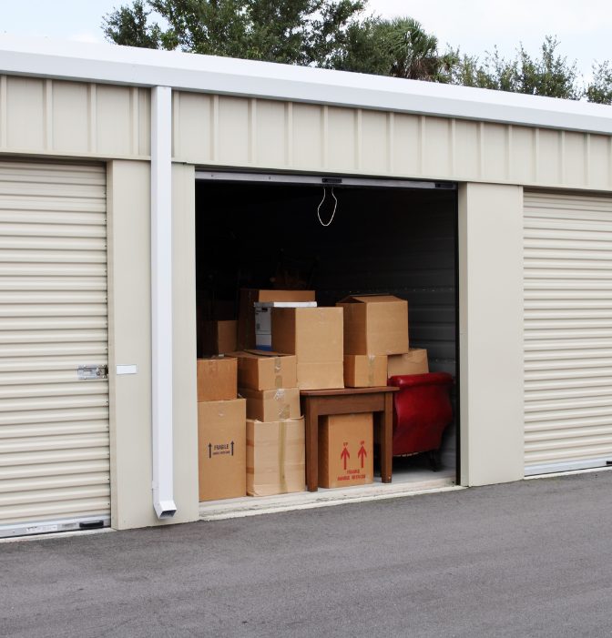 Loxon Graphic storage unit with roller door open and packed with supplies and moving boxes