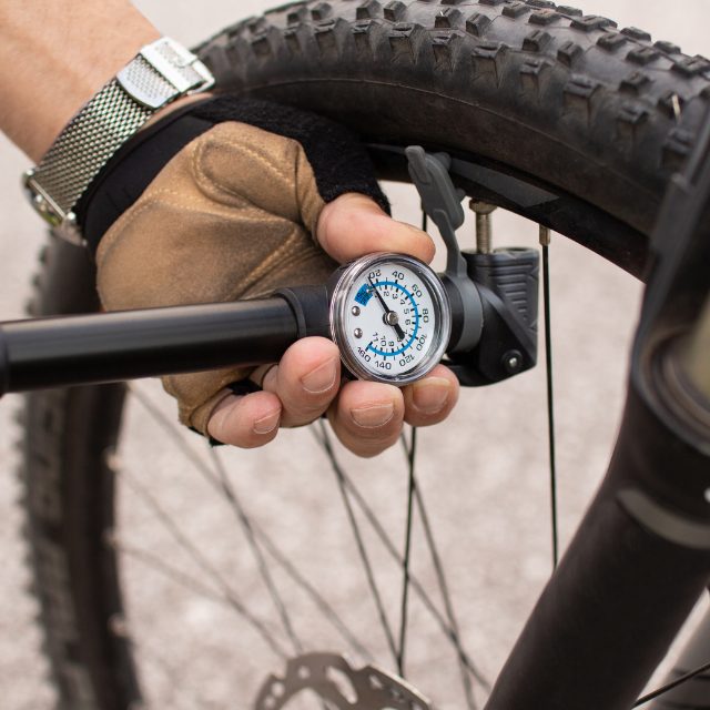 a man checking the air pressure on his bicycle tyres