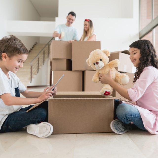 two children sitting in front of a Loxon Storage moving box and packing their belongings into a moving box