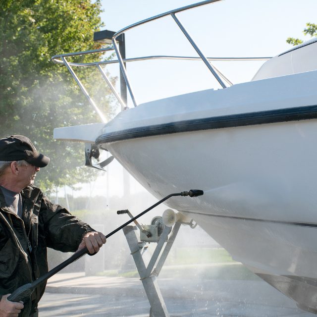 a man hosing down the boat's exterior