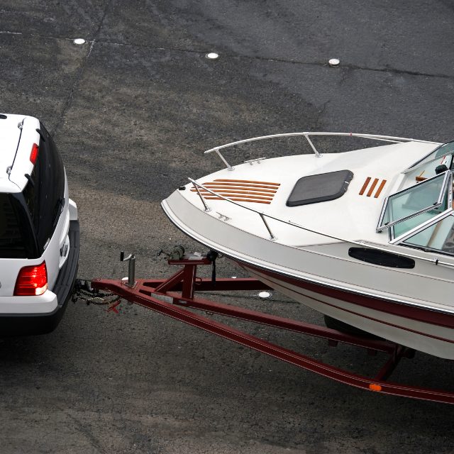 a boat on a trailer being towed by a car
